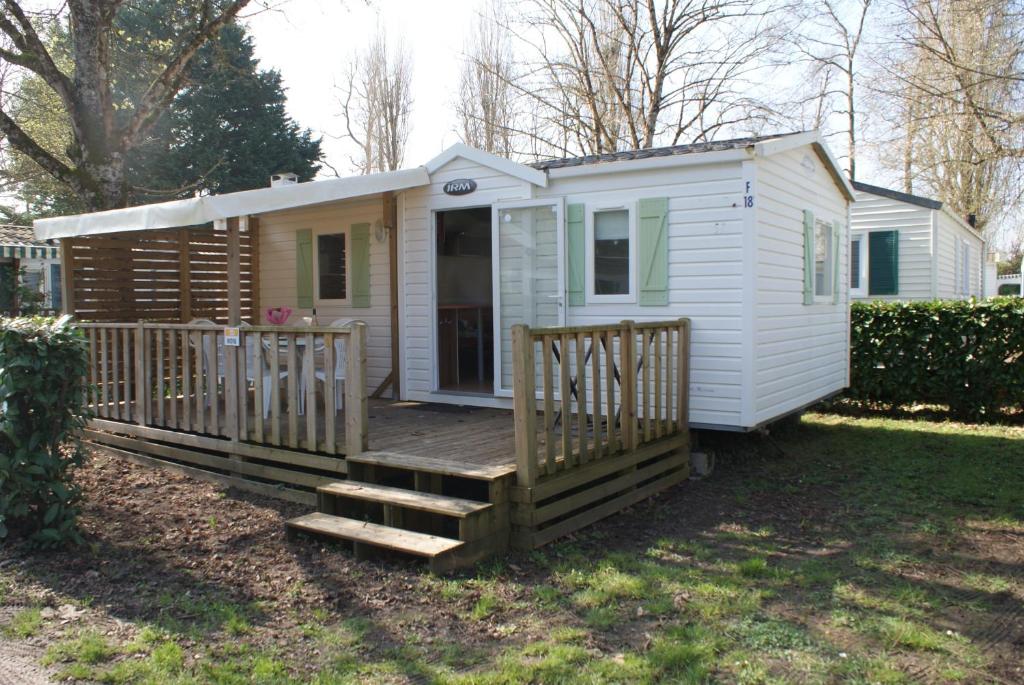 una casetta con portico e terrazza di Mobil-home équipé pour un séjour au vert avec piscine a Trogues