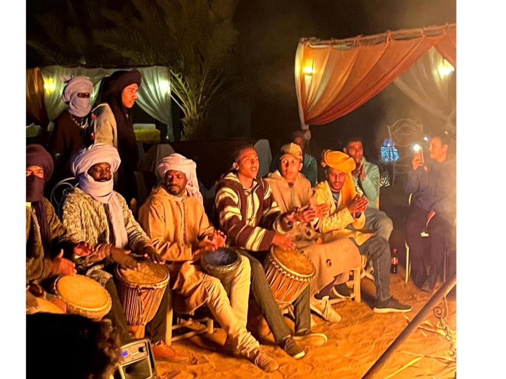 a group of people sitting in a group with drums at Moroccan Desert Camp in Merzouga