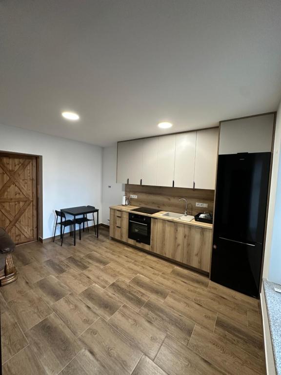 a kitchen with a black refrigerator and a table at Apartament przy sadzie in Szczytno