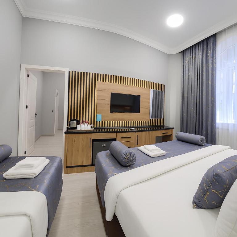 a hotel room with two beds and a flat screen tv at Old City Ganja in Ganja