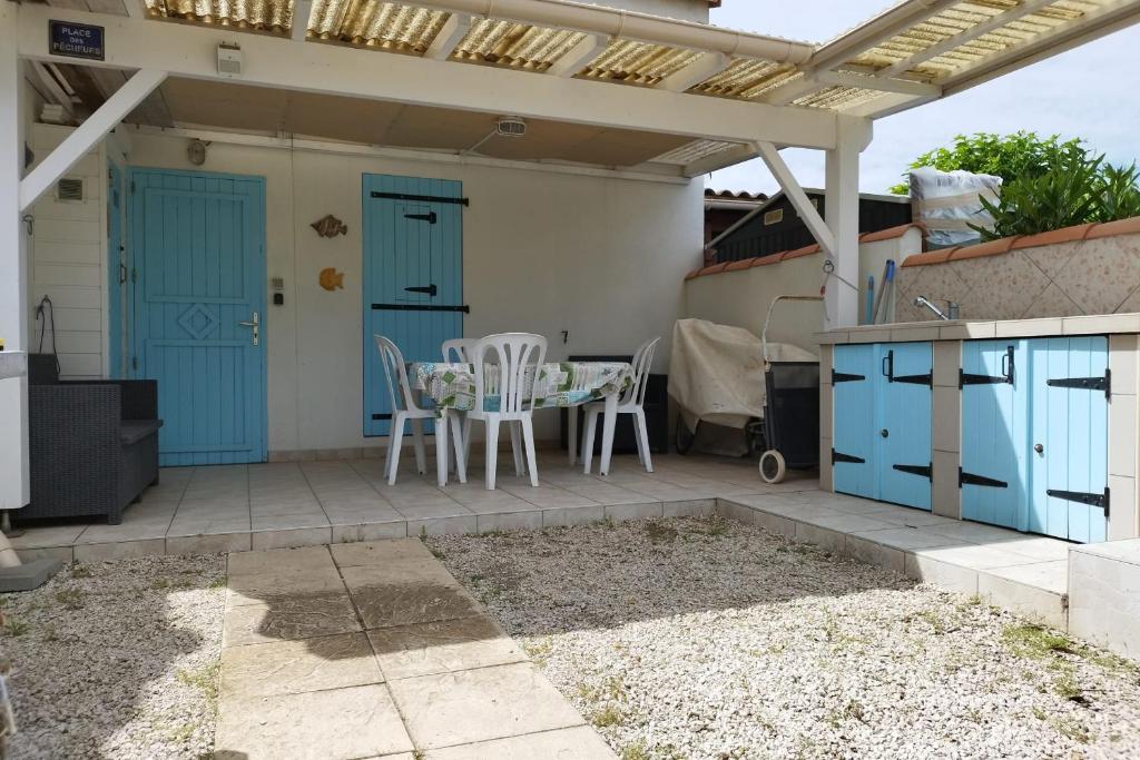 d'une terrasse avec des portes bleues, une table et des chaises. dans l'établissement Beach house, à Frontignan