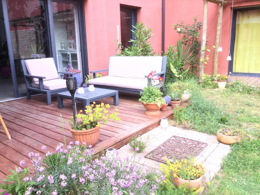 a wooden deck with a couch and some plants at L'hacienda in Champagné-les-Marais