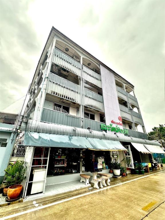 a tall white building with benches in front of it at อมรรัตน์Room in Pathum Thani