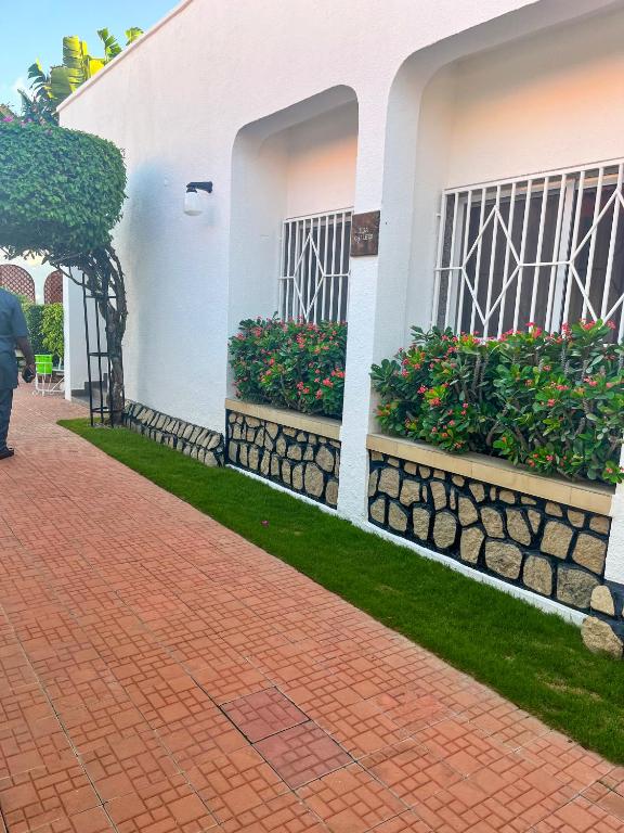eine Person, die an einem weißen Gebäude mit Blumenkästen vorbeigeht in der Unterkunft Signature Hotel Prince in Kano
