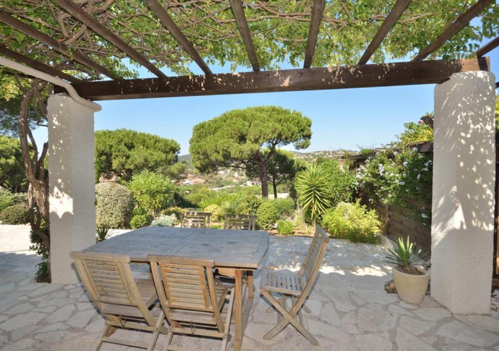 une table et des chaises en bois sur une terrasse dans l'établissement Villa- Mazet 59, à Sainte-Maxime