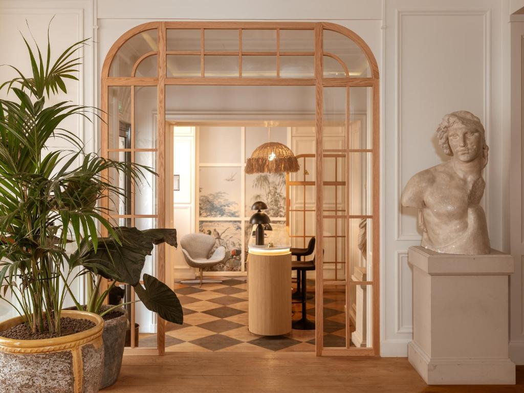 a room with a statue and a table with a chair at Hôtel Zélie in Paris