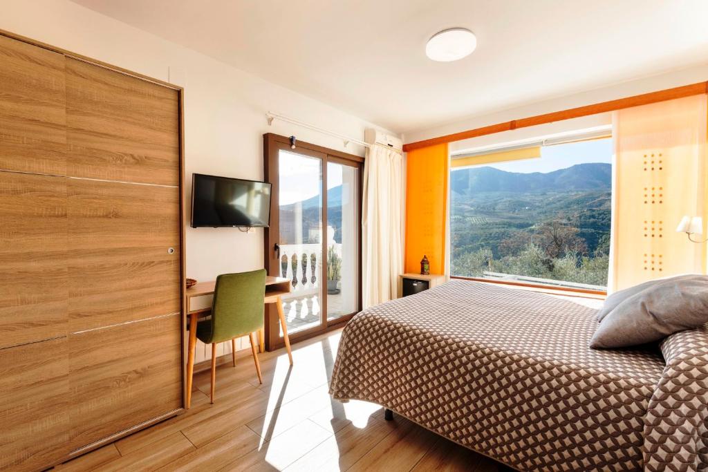 a bedroom with a bed and a large window at Hostal y Apartamento Rural Los Naranjos in Melegis