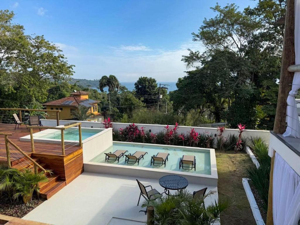 a backyard with a swimming pool and a patio with chairs at Santomar Guest House in Ilhabela
