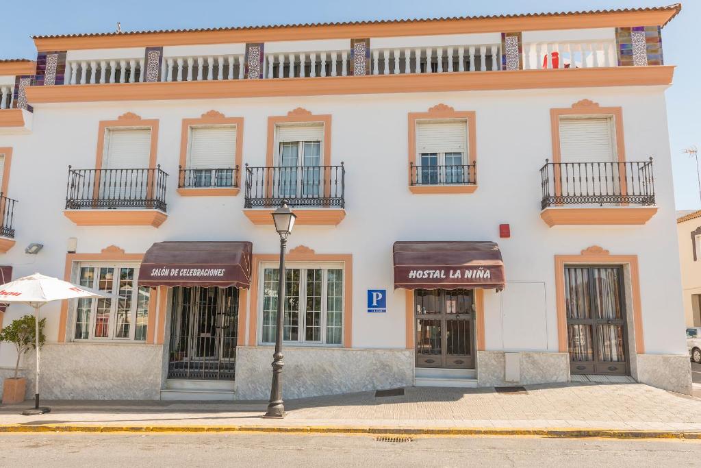 パロス・デ・ラ・フロンテーラにあるHostal Restaurante La Niñaの窓とバルコニー付きの白い大きな建物
