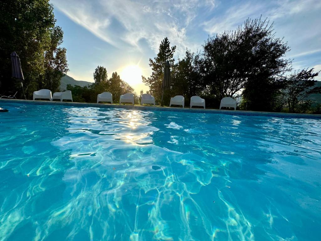a swimming pool with chairs and the sun setting at Ferme Fortia in Montréal-les-Sources