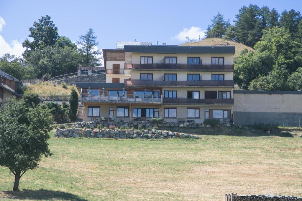 un bâtiment sur une colline avec un champ devant lui dans l'établissement Les Sorbiers Appartements, à Montricher-Albanne