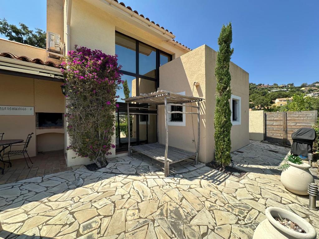 a house with a stone patio with an umbrella at LES TAMARIS Maison pour 6 personnes dans domaine privé avec piscine à La Londe-Les-Maures in La Londe-les-Maures