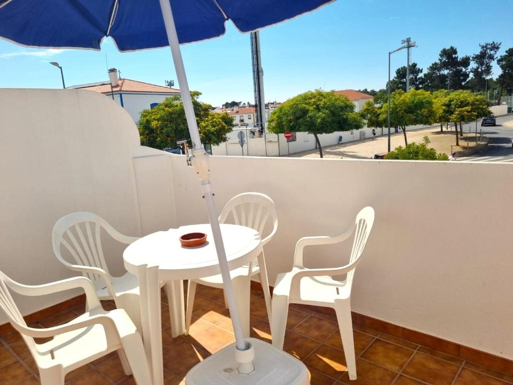 a white table and chairs with an umbrella on a balcony at CASA DO SOL by Stay in Alentejo in Vila Nova de Milfontes