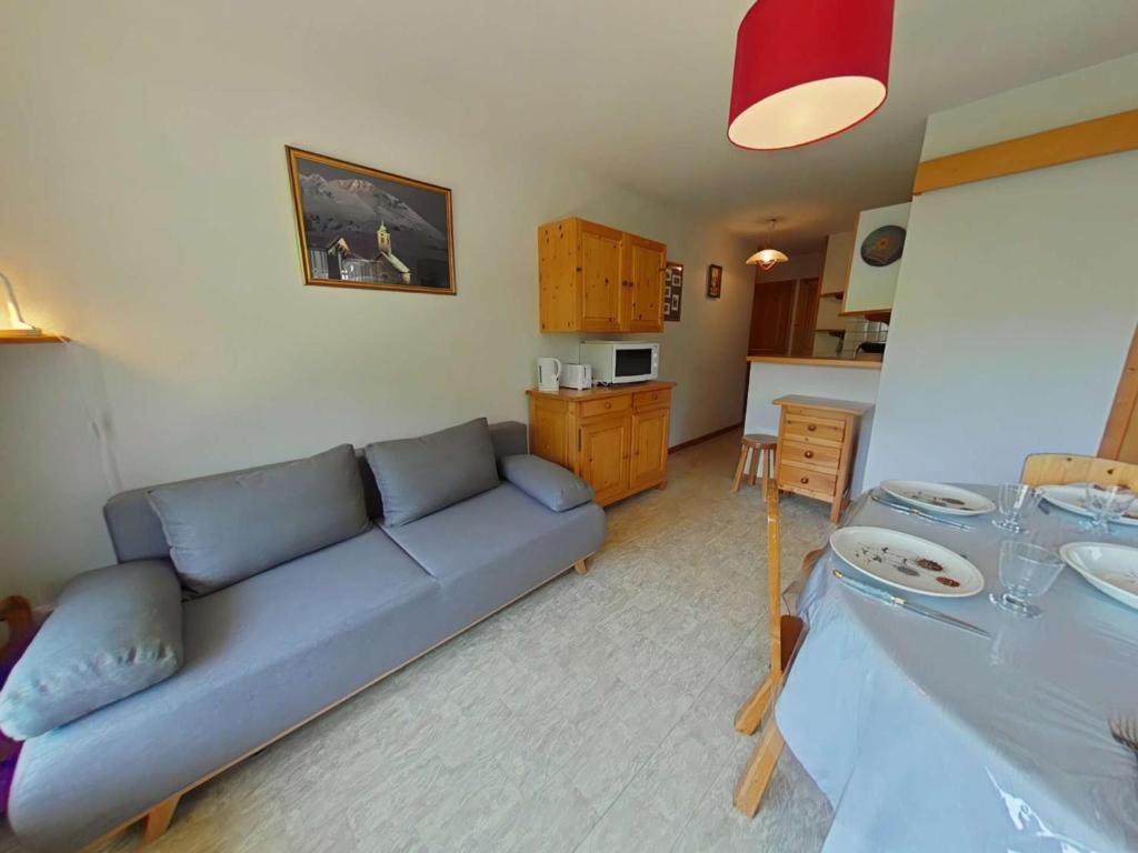 un salon avec un canapé bleu et une cuisine dans l'établissement Appartement 2 Pièces Cabine avec Balcon Sud - Proche Pistes et Commerces - FR-1-241-188, au Grand-Bornand