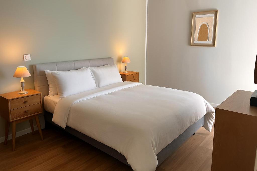 a bedroom with a large white bed and two night stands at Zenao Appart'hôtels Châlons-en-Champagne in Châlons-en-Champagne