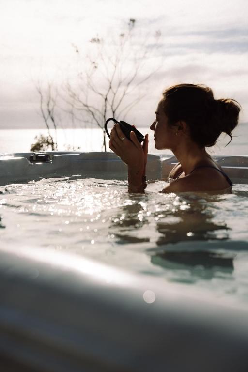 a woman is in a bathtub at Kauri Lodge -Luxury waterfront in Pouto