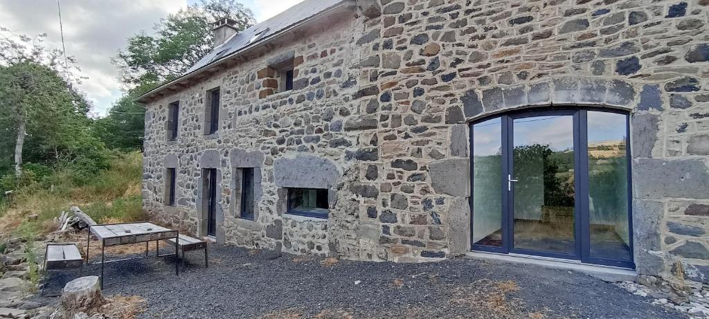 ein Steingebäude mit einem Fenster und einem Tisch draußen in der Unterkunft Cottage au cœur de l'Aubrac in Saint-Chély-dʼAubrac