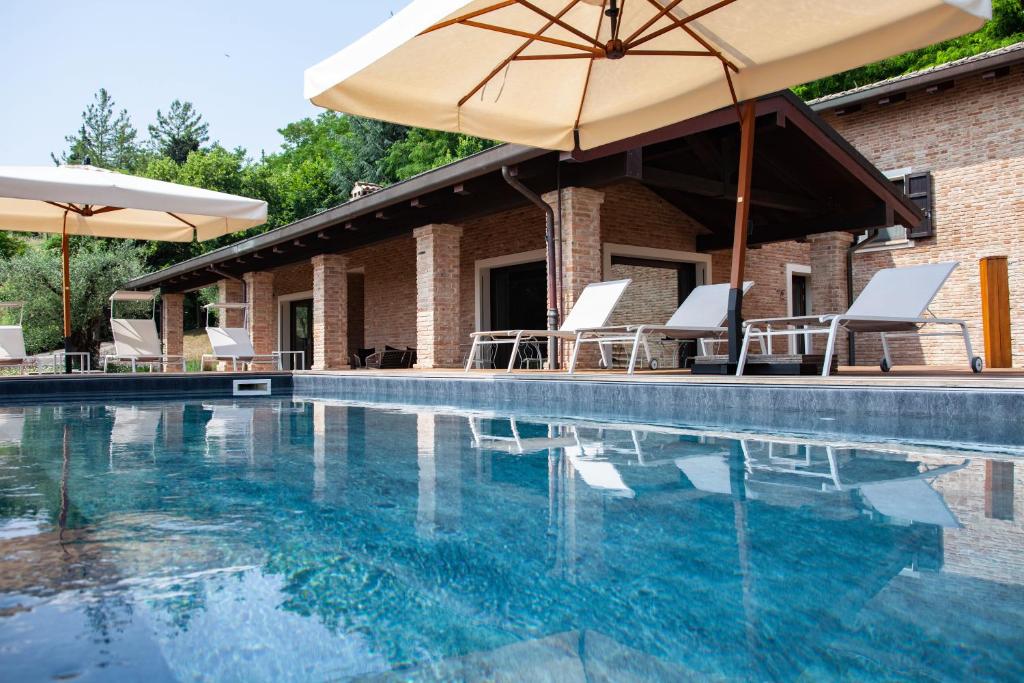 a swimming pool with chairs and an umbrella at Resort Villa Paola in Longiano