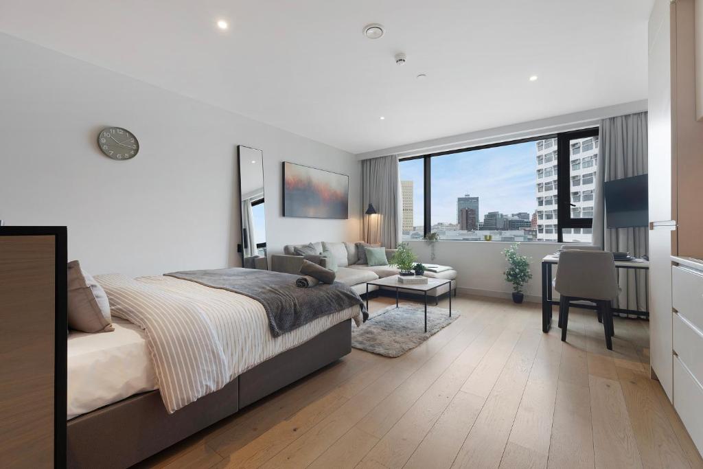a bedroom with a bed and a couch and a table at Stylish Studio in Citysuites in Manchester