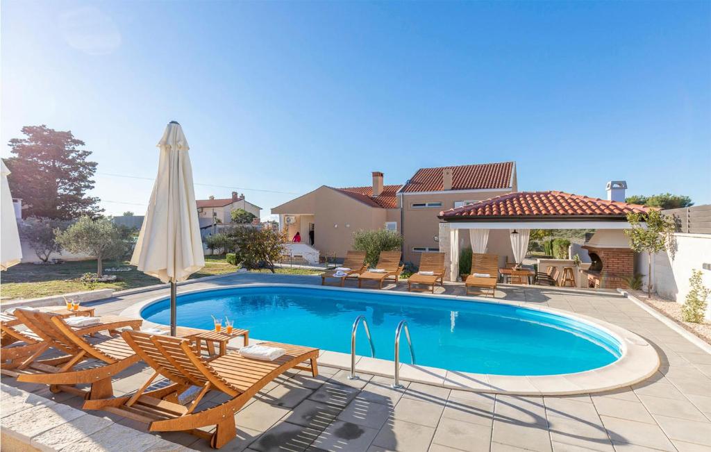 a swimming pool with chairs and an umbrella at Luxurious Home In Vrsi in Vrsi