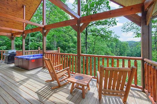 una terrazza in legno con 2 sedie e un tavolo su una cabina di Beary Cozy Holiday home a Gatlinburg