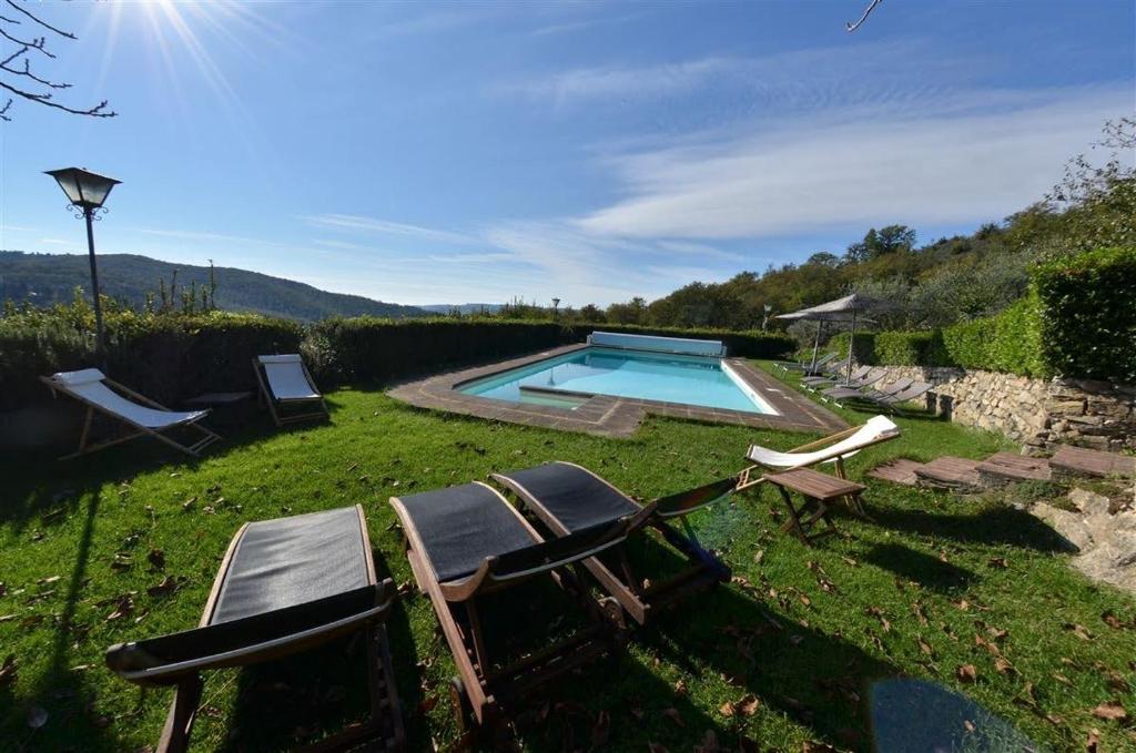 a yard with a pool and two lawn chairs at Celle di lecchi Porcilaia in San Sano