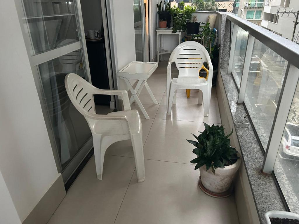 two white chairs and a table on a balcony at ECONÔMICO, qtos na BEIRA DA PRAIA, confortável in Balneário Camboriú