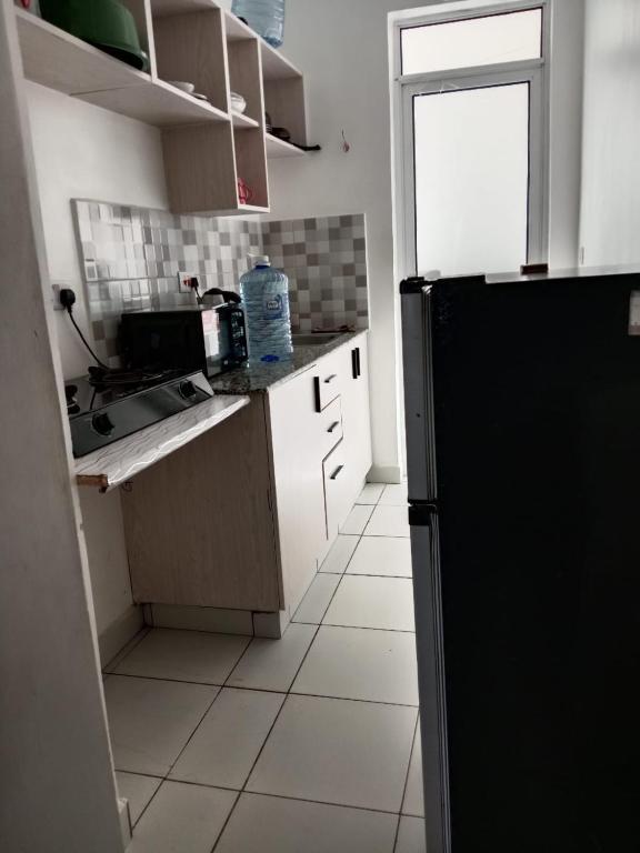 a kitchen with a black refrigerator and a tile floor at Buxton Point Kandy Classy Two Bedroom Apartment in Mombasa