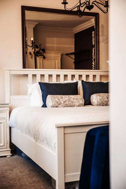 a bedroom with a white bed with a large mirror at Annex at The Stables in the Heart of England in Hinckley