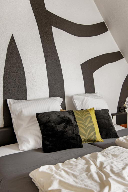 a bedroom with a bed with two pillows and a wall at La Maison ERNENWEIN in Obermodern