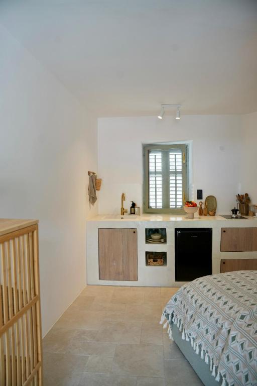 a white kitchen with a bed and a sink at mi sestre – Studio Apartment Hvar Vrisnik in Jelsa