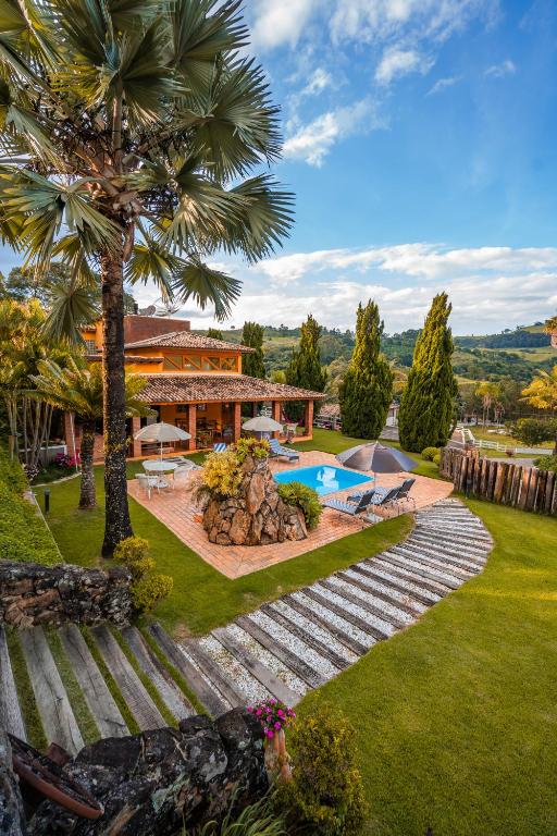 a house with a palm tree and a swimming pool at Pousada Vale do Café in Bueno Brandão