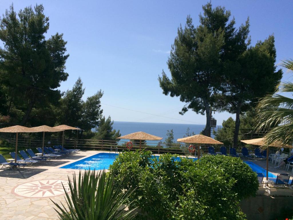 a swimming pool with chairs and umbrellas at Thea Hotel in Possidi