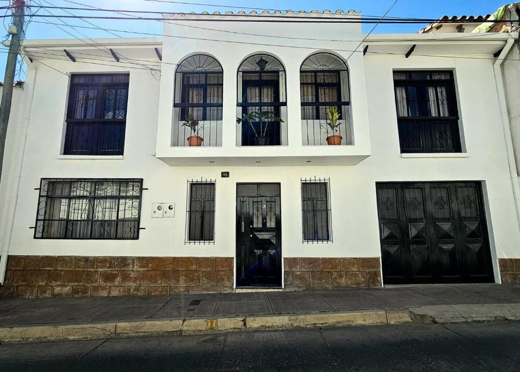 a white house with black doors and windows at Santa Teresa Alley Hostel in Sucre