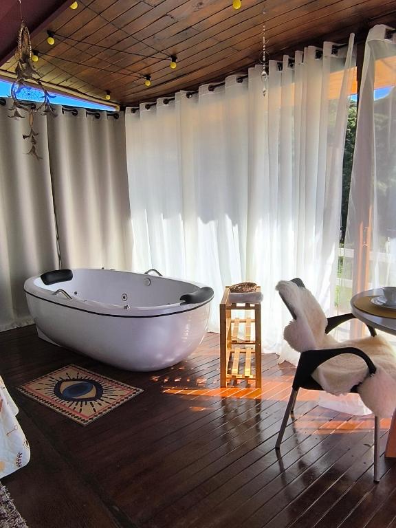 a white bath tub sitting in a room with a window at Chalés Recanto dos Sonhos in Camanducaia