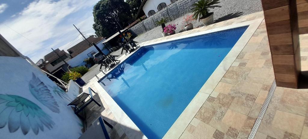 a large blue swimming pool next to a building at Pousada Sossego com piscina em Bertioga in Bertioga