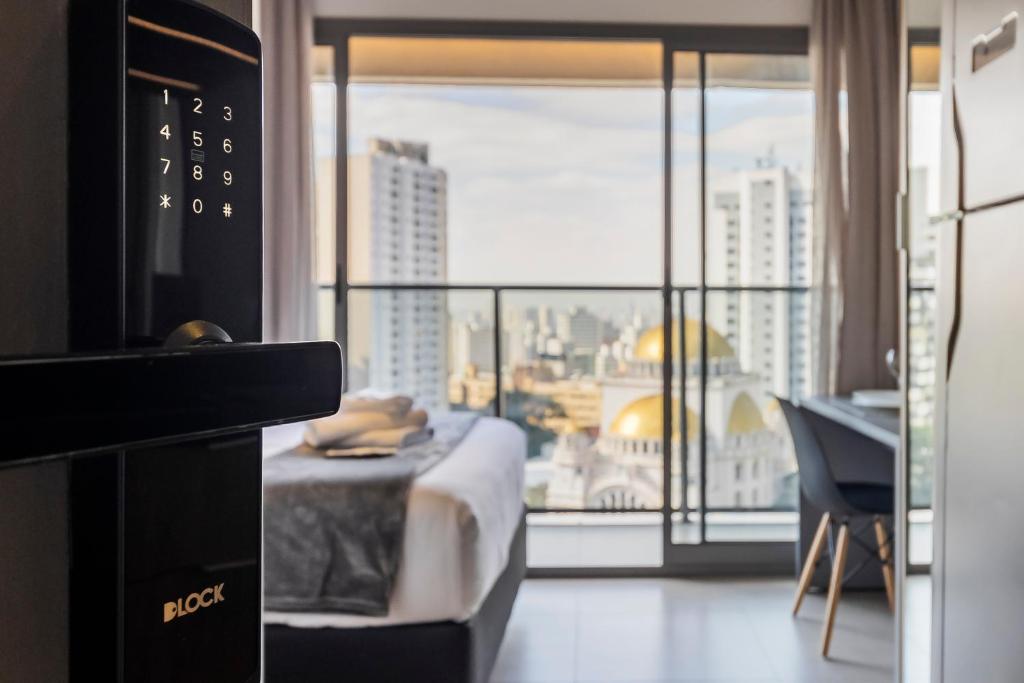 a hotel room with a bed and a view of a city at Yume On Paulista in São Paulo