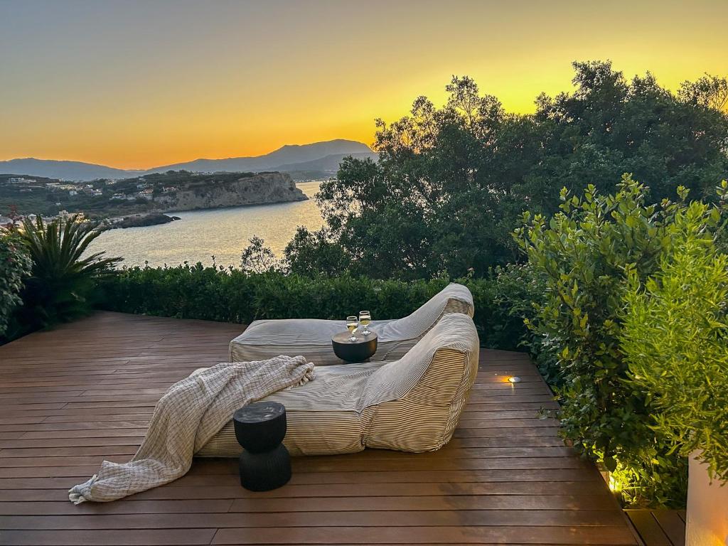 a rattan couch on a deck with a view of the ocean at Crete Beachfront Coconut Gem with SeaViews & Pool in Almyrida
