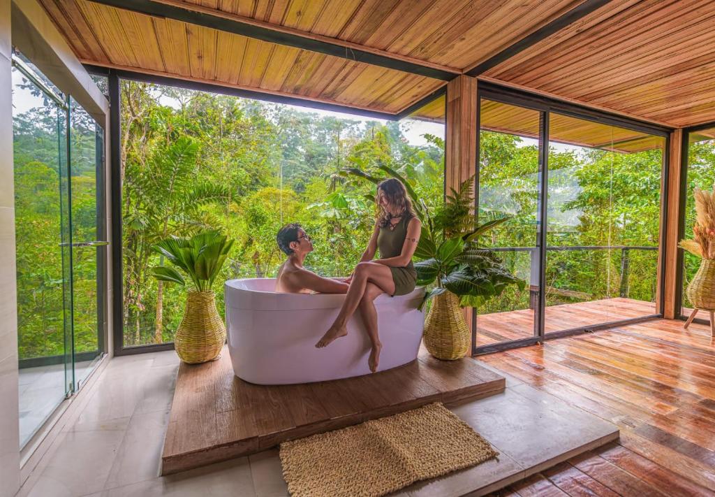 a man and woman sitting in a bath tub on a porch at Suite Alpayaku, Suite Boutique Privada con Desayuno Incluido, Cedro Amazon Lodge in Mera