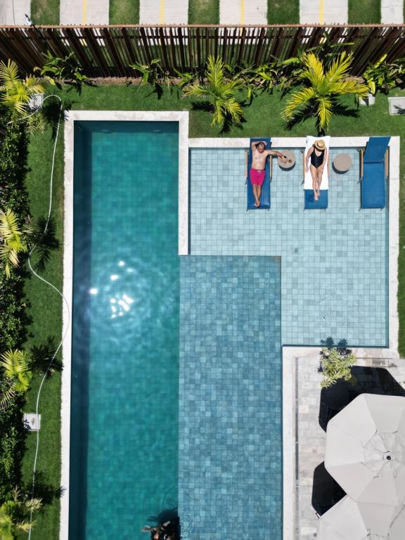 two people standing next to a swimming pool at Maré Alta Beach Hall by AFT in Tamandaré