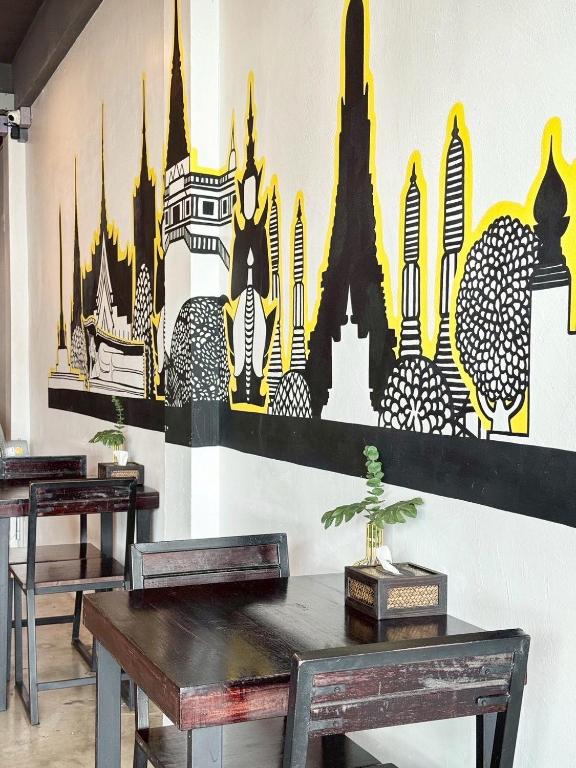 een eetkamer met twee tafels en een muur met steden bij EK Silomhostel in Bangkok