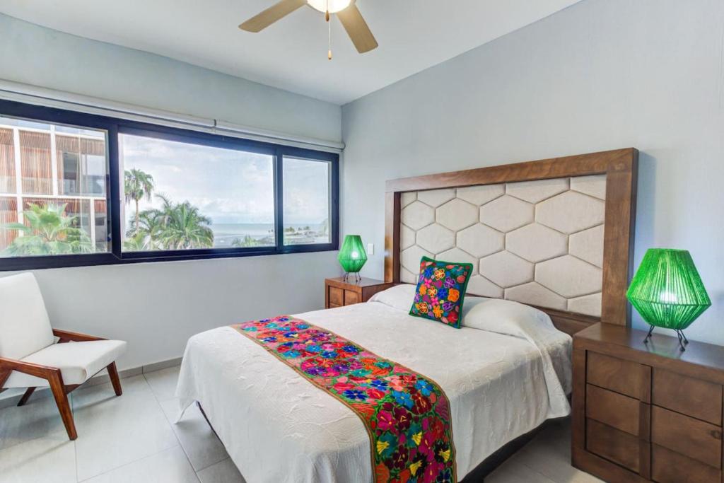 a bedroom with a bed and a chair and a window at 2BD Condo with Roof shared Pool in Cruz de Huanacaxtle
