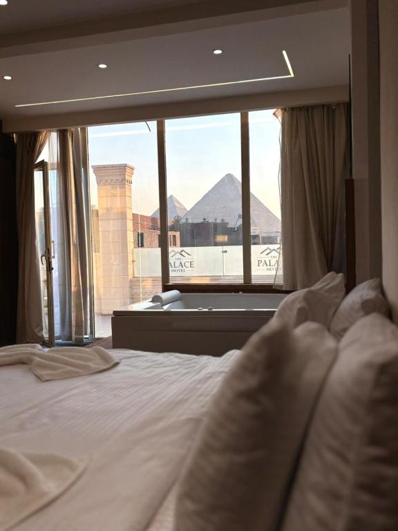 ein Schlafzimmer mit einem Bett und einem großen Fenster in der Unterkunft Ra Palace Pyramids View Hotel in Kairo