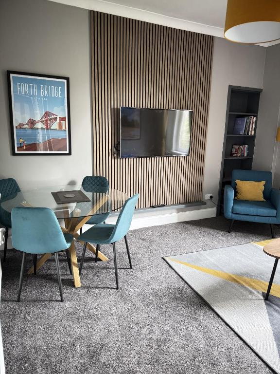 a living room with a table and chairs and a television at 56 Degrees North in Kirkcaldy