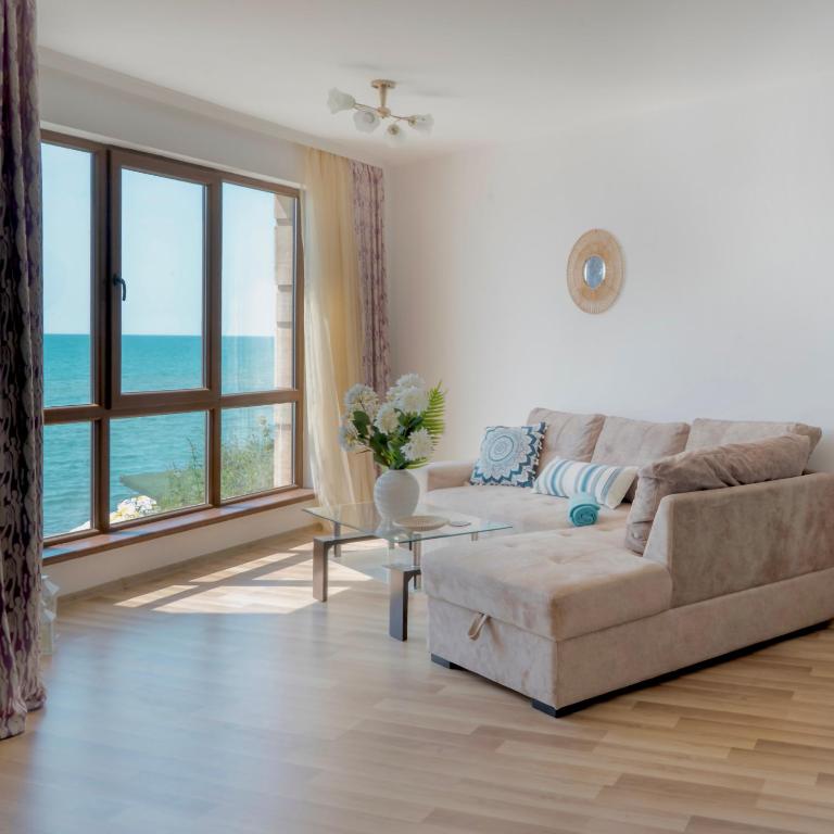 a living room with a couch and a large window at CABA Apartment in Varna City