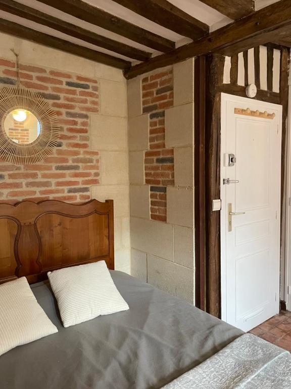 une chambre avec un lit et un mur de briques dans l'établissement Appartement Des Lingots, à Honfleur