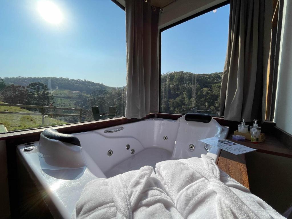 Una bañera en una habitación con una ventana grande. en Chalé Causo Bão, en Gonçalves