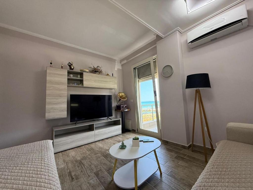 a living room with a couch and a tv and a table at Coco Apartments in Vlorë