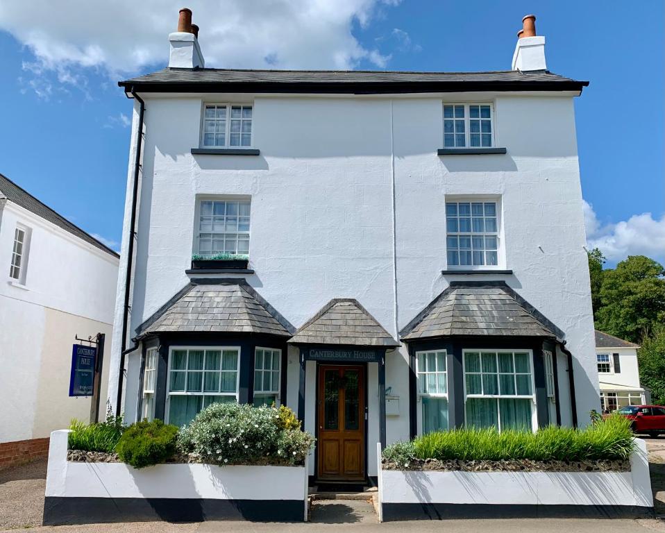 Casa blanca con puerta y ventanas marrones en Canterbury House, en Sidmouth