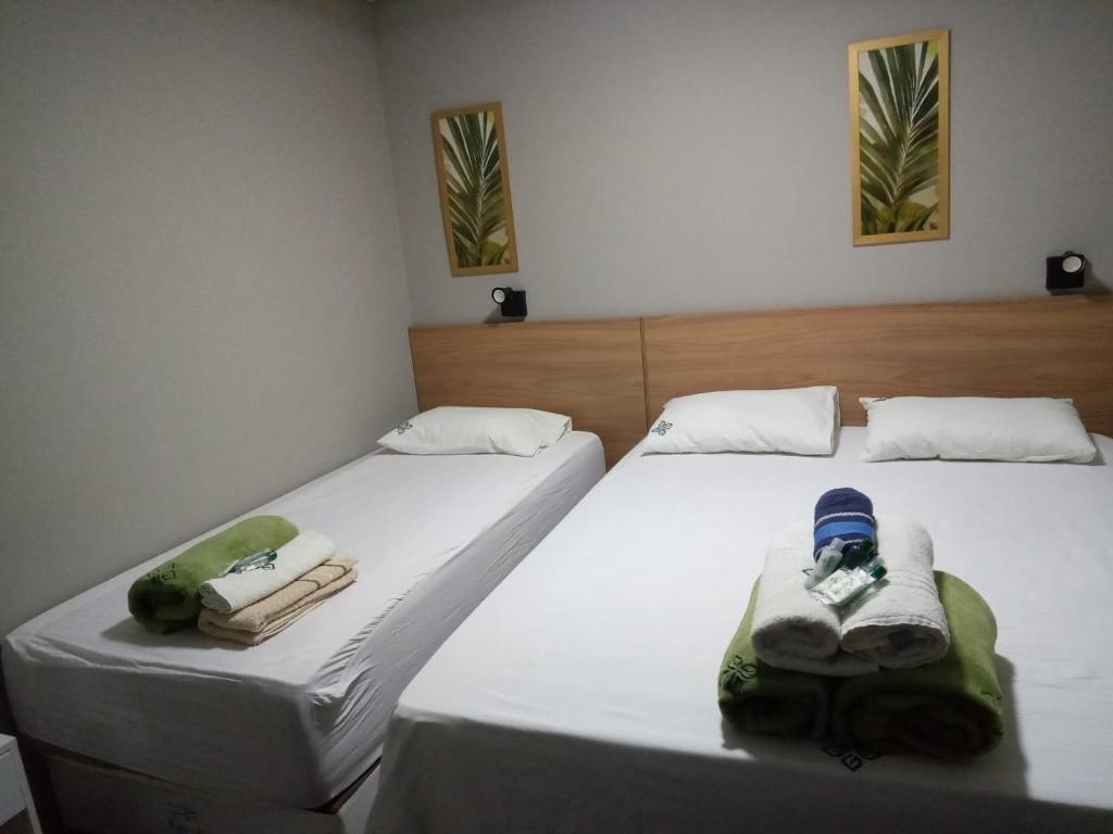 two beds with towels and shoes on them in a room at Zuppolini Hotel in Bananeiras
